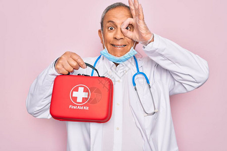 戴着听诊器和医用面罩的老年英俊老医生手持急救箱图片