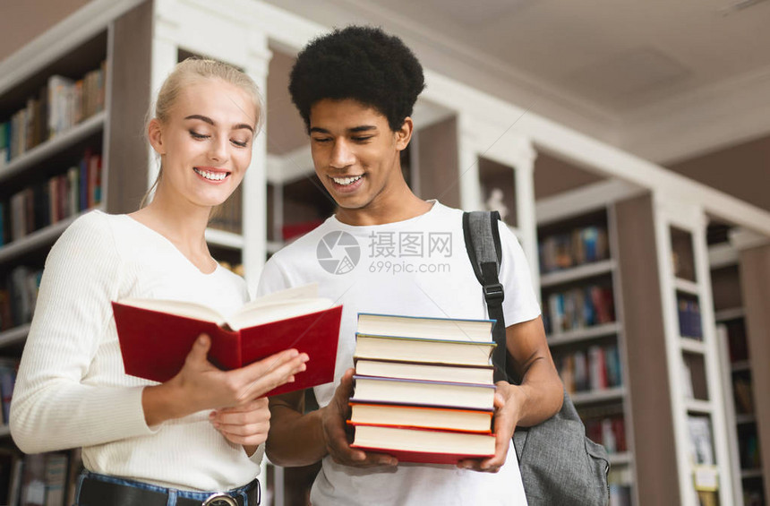 多种族青少年情侣在图书馆谈论书免图片