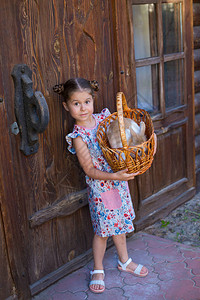 女孩站在一个老木农房的门旁边把兔图片
