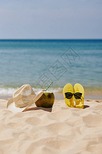 沙滩上有拖鞋太阳眼镜美味的椰子鸡尾酒图片