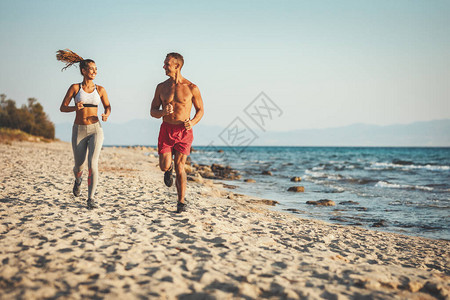 一对微笑的情侣正沿着海边奔跑在夏日阳光明媚图片