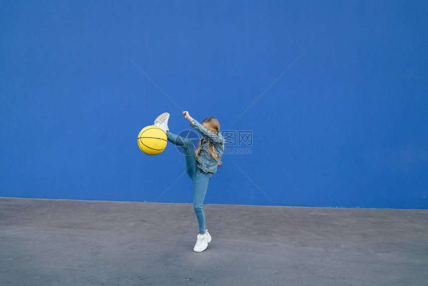小女孩玩黄色球和蓝色背景图片