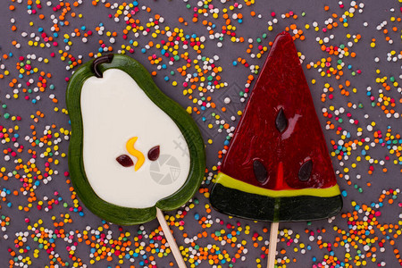 梨和西瓜形状的棒糖大美味棒糖和彩色洒在黑色图片