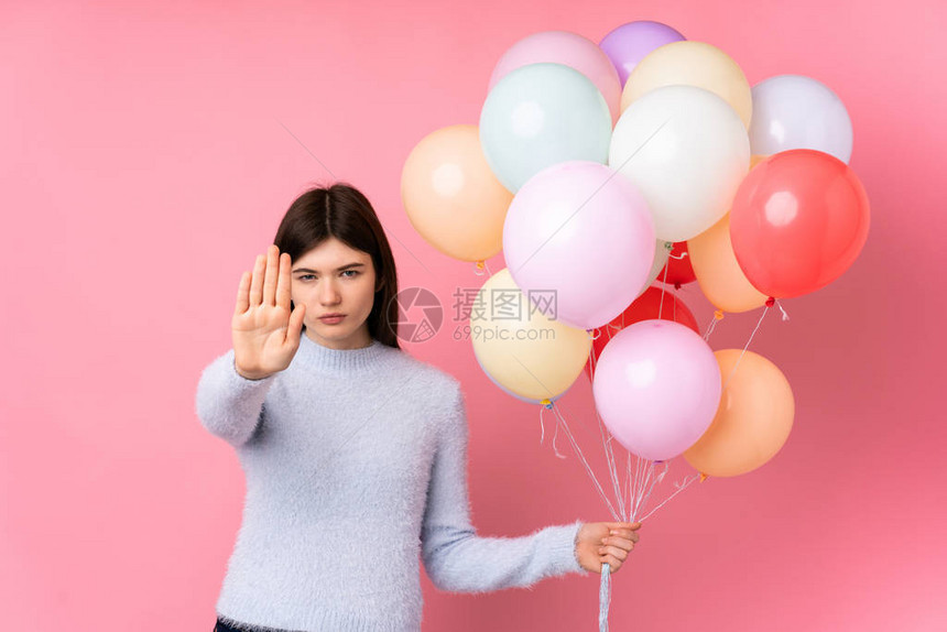 乌克兰年轻少女拿着大量的气球与孤立的粉红背景相隔绝用她的手图片