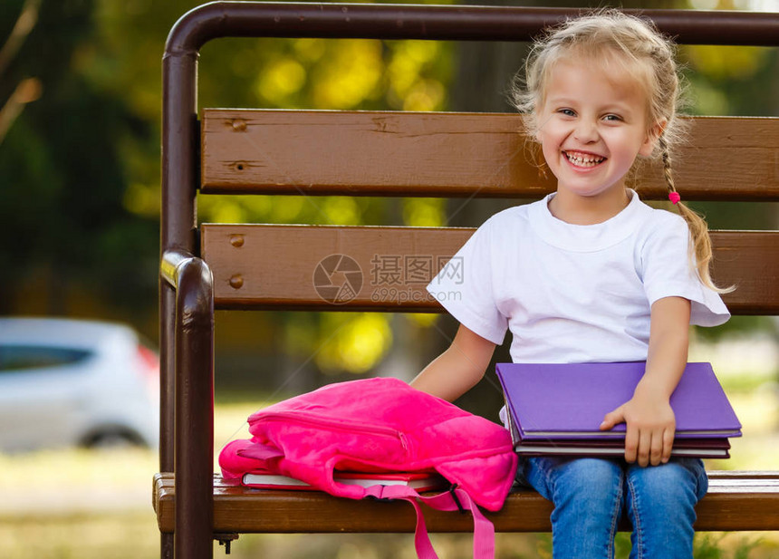 一个背着包的小女孩坐在长椅上图片