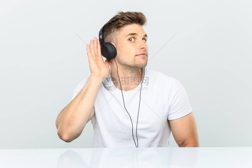 年轻人用耳机听音乐试图听到八卦但是图片