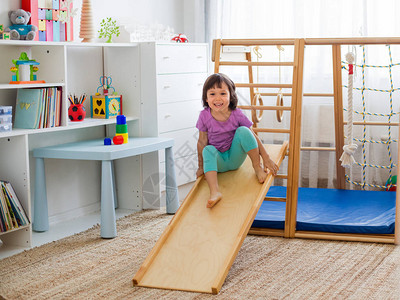 小女孩在木制家庭体育游戏大楼梯戒指和绳索上骑过山车玩得开心儿童体育锻炼在家对孩子背景图片