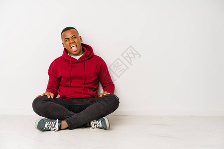 坐在地板上的年轻拉丁男子孤立的滑稽和友图片