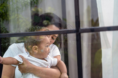 亚洲幸福家庭场景母亲在屋窗旁抱男婴家庭图片
