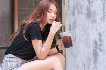 快乐的年轻女子拿着杯苏打水冰与复制空间快乐的女孩喝冷可乐口渴在她看图片
