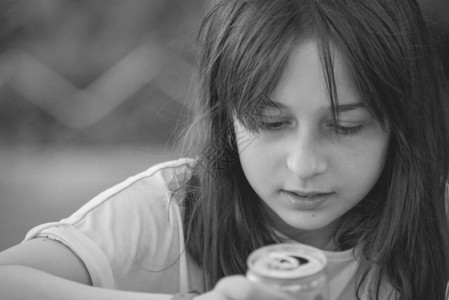 年轻女孩喝水十几岁的女孩用铁罐喝酒一个9岁的女孩手里背景图片