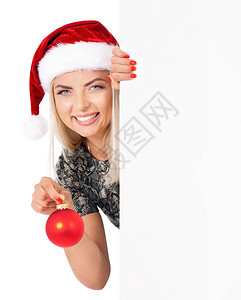 美丽的女人在的帽子拿着圣诞树装饰球和空板图片