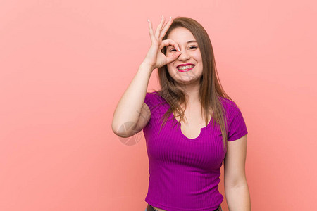年轻的西班牙女人对着粉红色的墙兴奋地保持正确图片