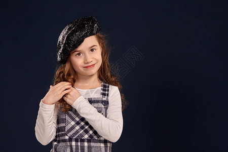 优雅的小女孩穿着方格裙白色衬衫和黑色闪发光的贝雷帽图片