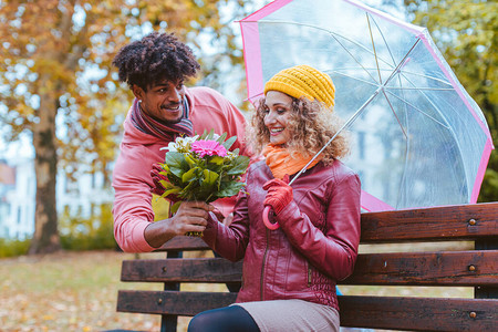 男人在暴风秋天用一束鲜花给他妻子带来欢乐给图片