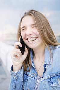 穿着戴尼姆夹克的年轻女孩在电话上聊天和笑交流与朋友沟通图片