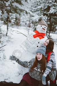 与雪人一起拍照的快乐女孩们图片