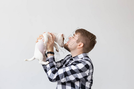 年轻人在白色背景上亲吻杰克罗瑟尔小狗Russell图片