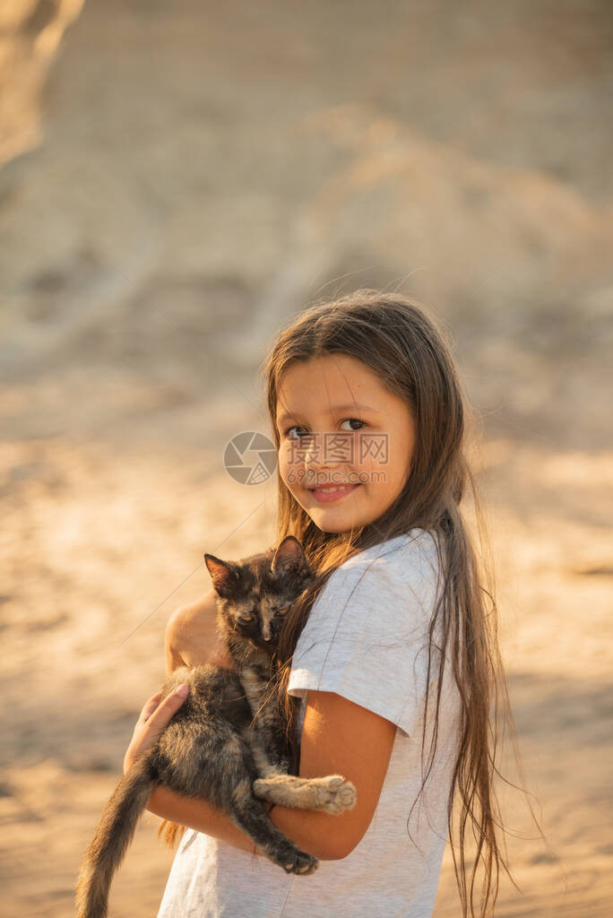 幼女在日落的光照耀着一只小猫宠物朋友生活方式与猫玩耍的图片