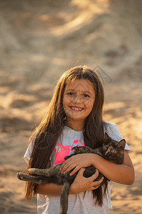 幼女在日落的光照耀着一只小猫宠物朋友生活方式与猫玩耍的图片