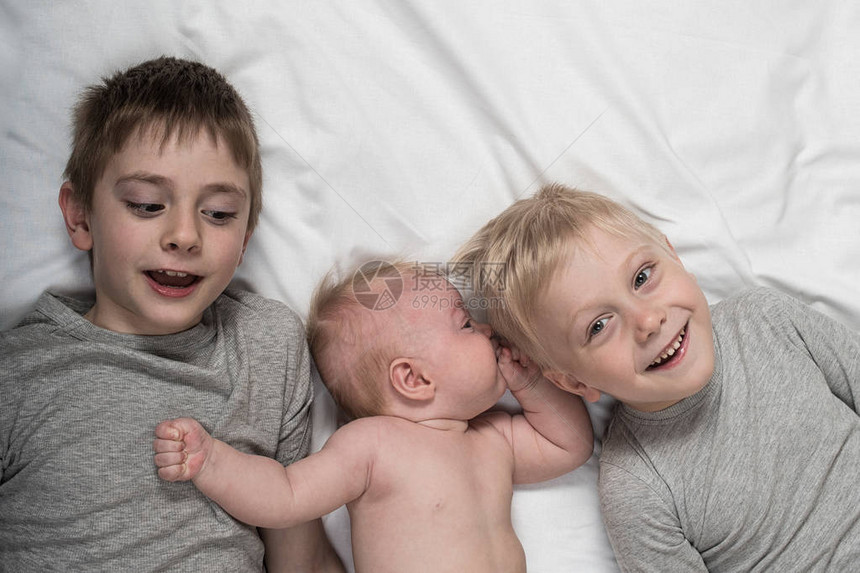 两个哥在白床上和最小的婴儿玩笑图片