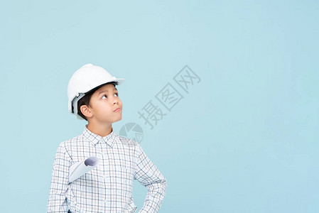 带着白头盔的怀疑工程师男孩仰望着蓝背图片