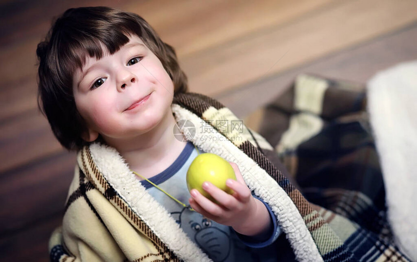 一个小卷发男孩的画像一个裹在地毯里的孩子吃一个苹果一个两岁的男图片