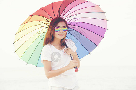 美丽的女人拿着彩虹多彩的雨图片