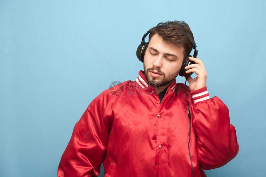 一个成年男子的特写肖像在蓝色背景上闭着眼睛听耳机里的音乐音乐爱好者喜图片