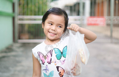 亚洲儿童可爱或小女孩微笑着拿塑料袋购物图片