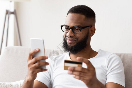 快速的网上购物乐趣微笑的非洲裔美国人用电话图片