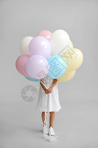 灰色背景中带气球的小女孩图片
