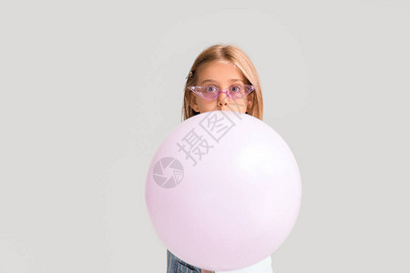 惊讶的小女孩带着灰色背景的气球图片
