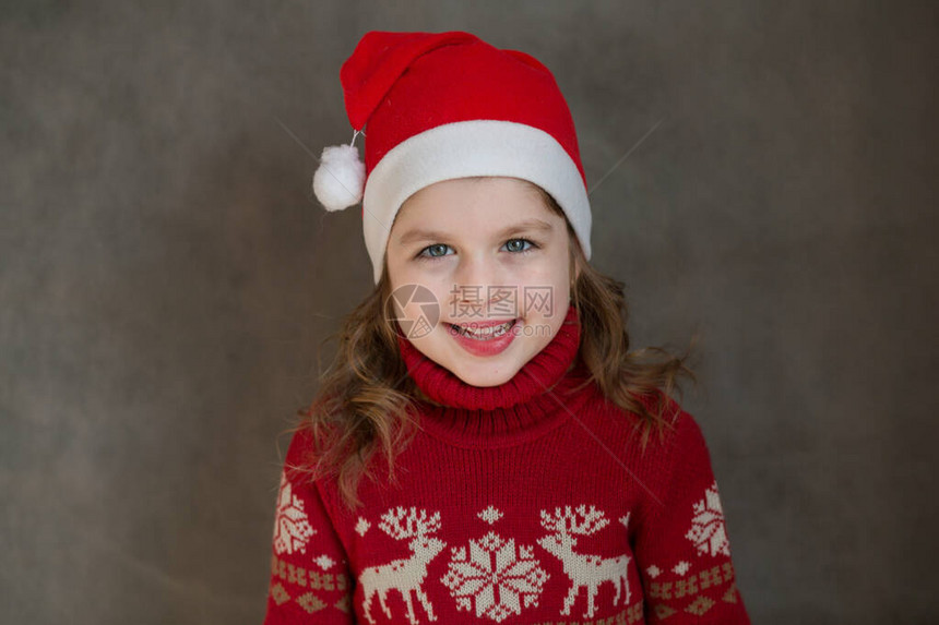 穿着圣诞夹克和圣塔帽子的快乐小女孩图片