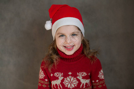 穿着圣诞夹克和圣塔帽子的快乐小女孩图片