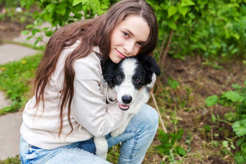 微笑的年轻迷人的女人可爱的小狗边境牧羊犬在夏季城市公园户外背景女孩新可爱的家庭成员宠物护图片