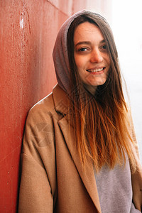 一个年轻女孩身着棕色大衣和眼镜在街上图片