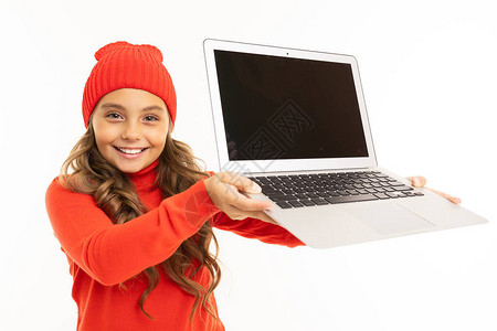 穿着红色毛衣和帽子的可爱小女孩用笔记本电脑在白图片