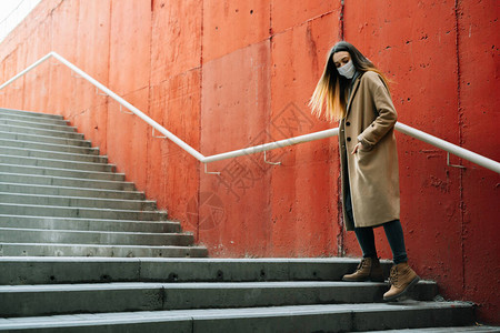 一个年轻女孩身着棕色大衣和眼镜在街上图片