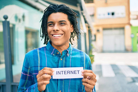年轻非裔美国人笑着快乐地在城市街道上拿着网络文字纸图片