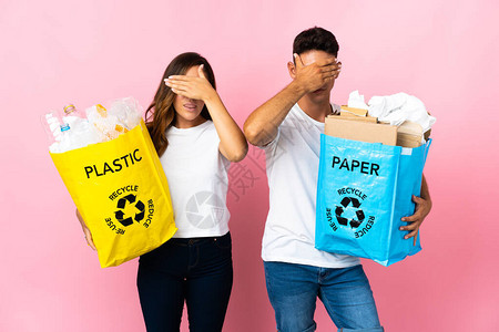 年轻夫妇拿着一袋塑料和纸的袋子图片