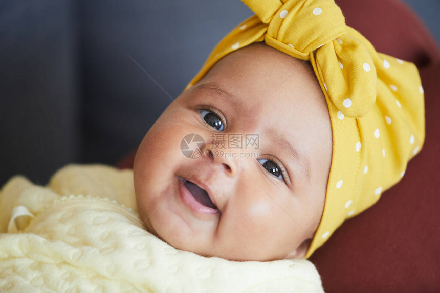 头上戴着蝴蝶结的可爱女婴看着相机的肖像图片