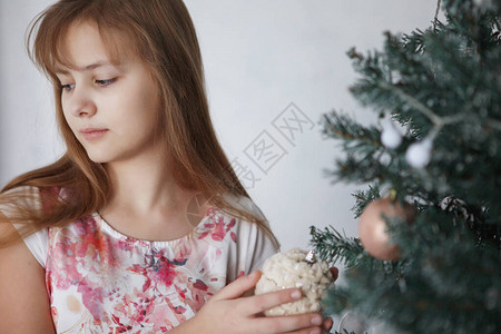年轻女孩在圣诞树附近一个长发穿多彩裙子的青少年装背景图片