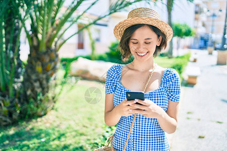 年轻美丽的女孩在城市街道上用智能手机行走路图片