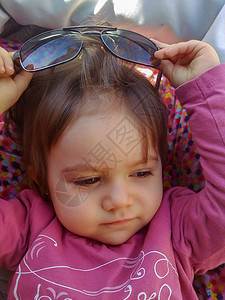 一岁的女婴坐在婴儿车里盯着她脱下母亲的墨图片