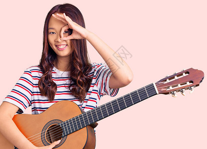 年轻漂亮的女孩弹着古典吉他图片