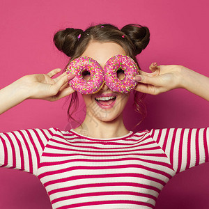 漂亮的女人和甜圈玩得开心花彩粉红色图片