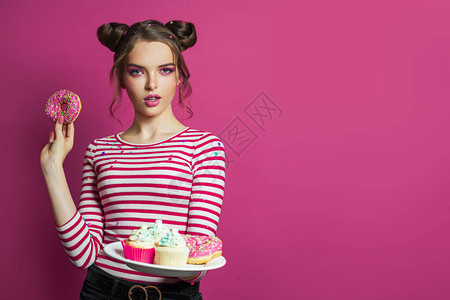 漂亮的时装模特女模特儿在生动的粉红背景上提供餐盘和图片