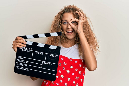 美丽的caucasian年轻女孩拿着视频电影拍手掌板图片