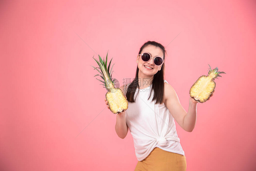 一个时髦女人的肖像粉红背景手上拿着菠萝图片